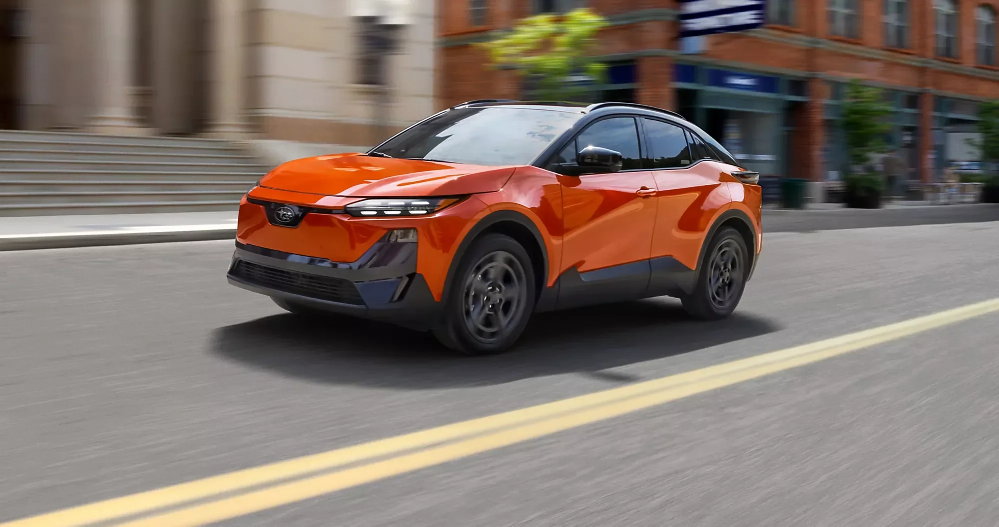 An orange Subaru on a city street.
