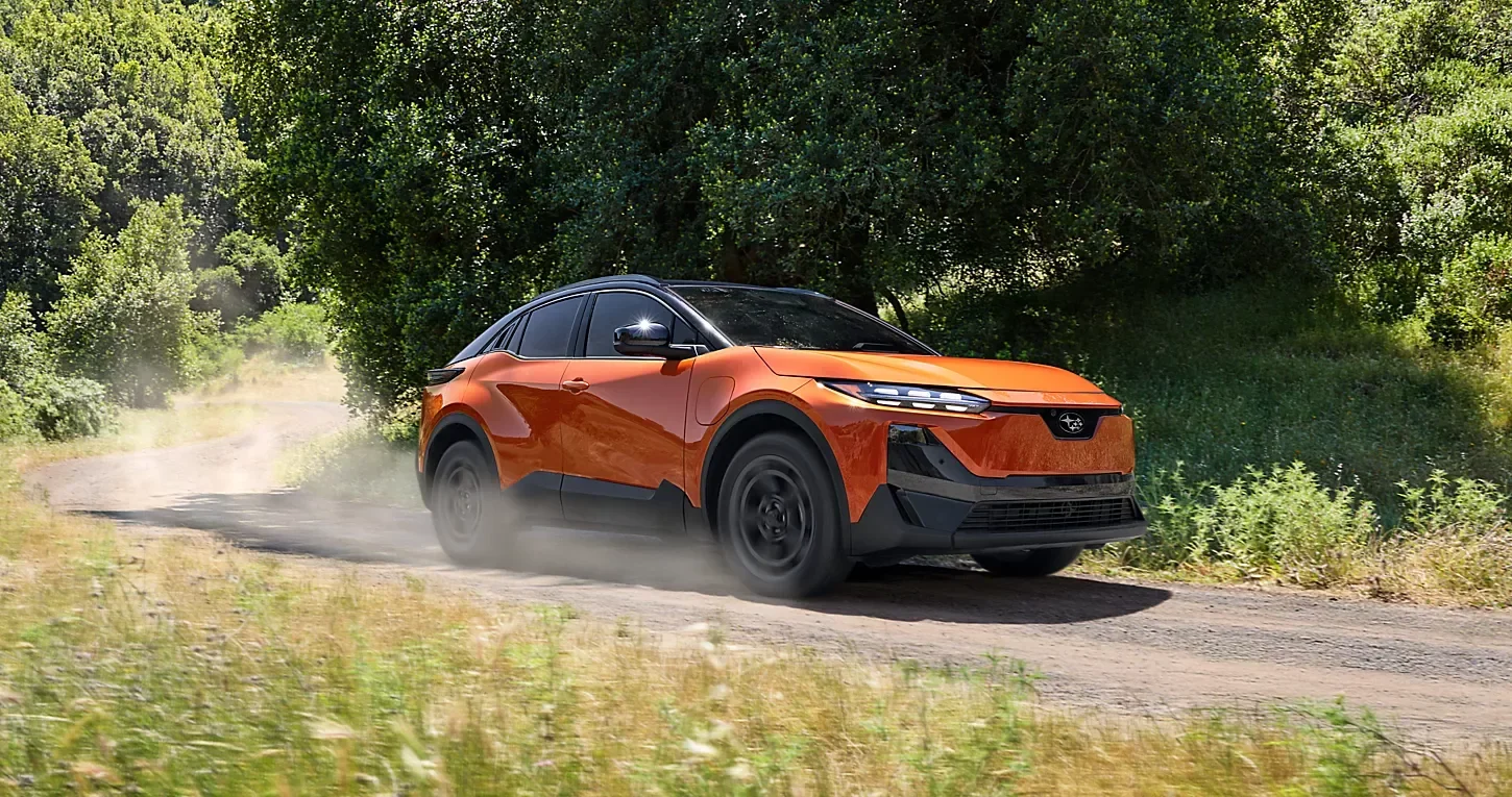 An orange Subaru on a dirt track, throwing up dust.