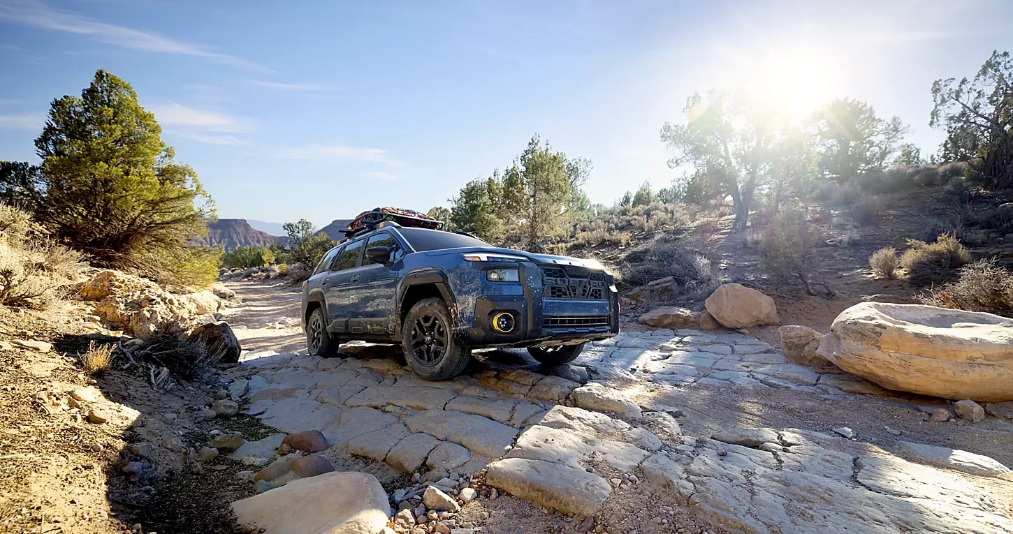 A Subaru Outback crossing a rocky creek bed.