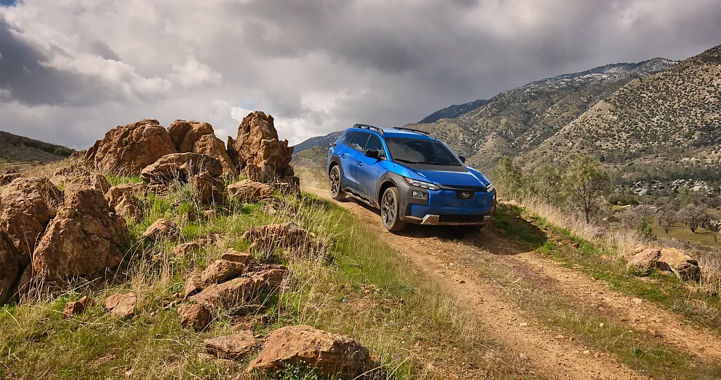A blue Subaru Crosstrek climbing a rocky trail.