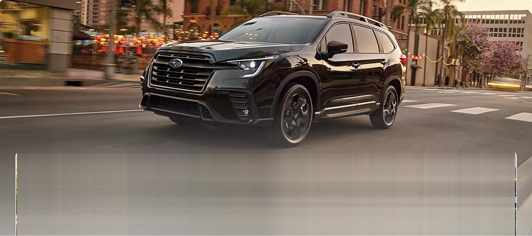 2026 Subaru Ascent driving a city street at dusk