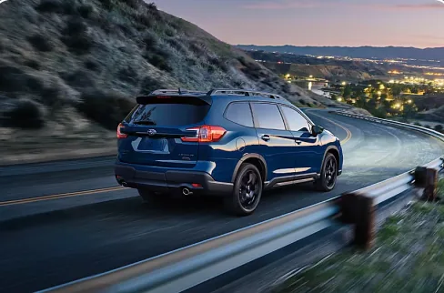 Blue 2026 Subaru Ascent on a hillside highway at dusk