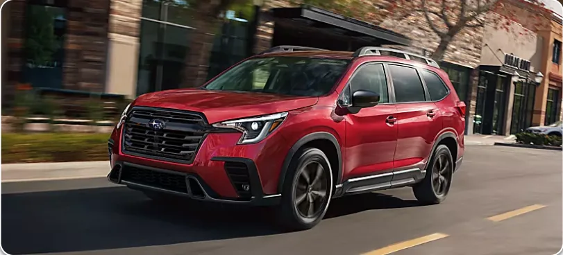 Red 2026 Subaru Ascent driving through a town centre
