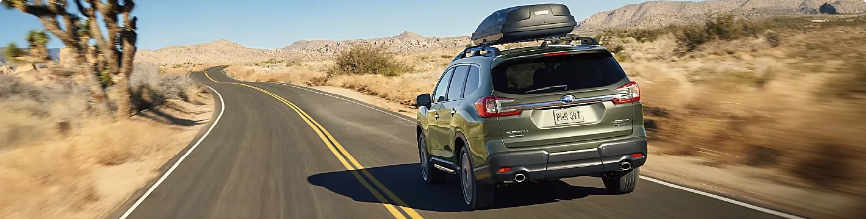 Green 2026 Subaru Ascent with a roof cargo box on a desert highway