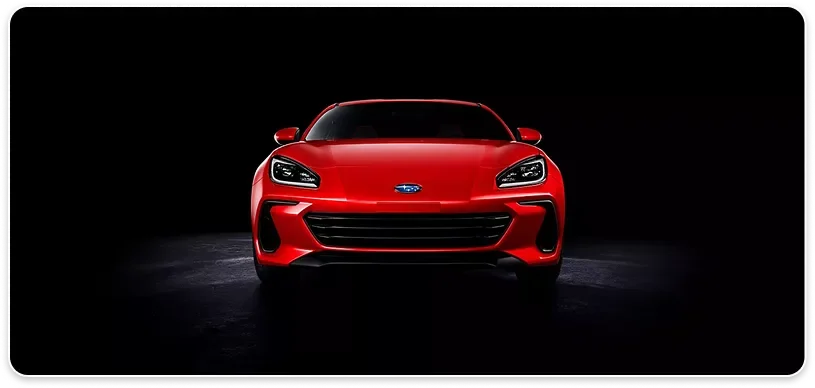 Red 2026 Subaru BRZ lit from the front against a black backdrop
