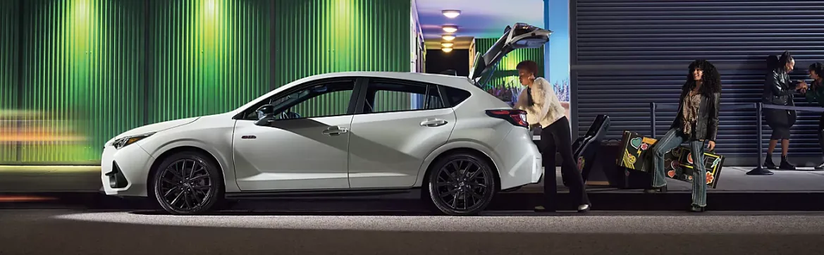 Subaru hatchback parked at an evening street event