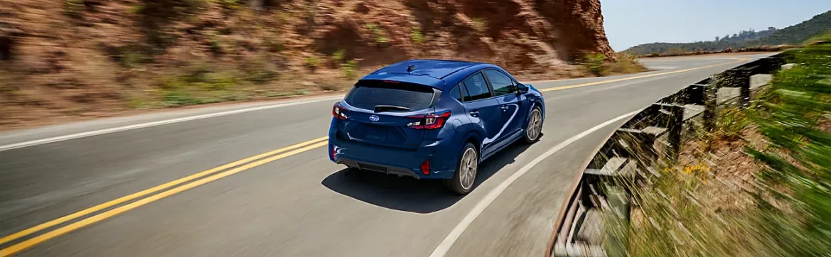 Blue Subaru travelling a winding canyon road