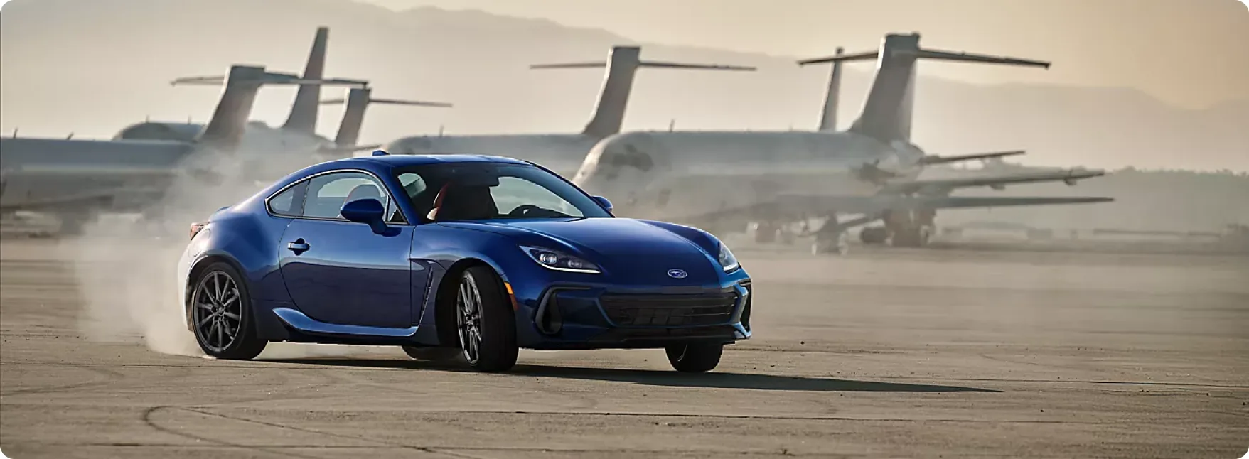 Blue 2026 Subaru BRZ drifting on an airfield past parked aircraft