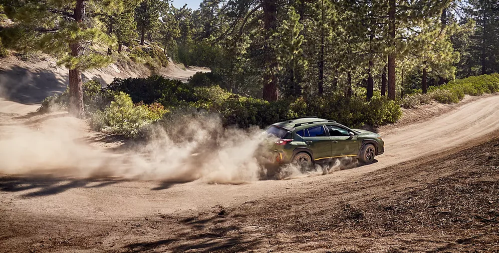 Green 2026 Subaru Crosstrek powering through a dusty corner on a dirt road