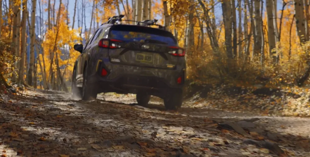 Grey 2026 Subaru Crosstrek climbing a rutted trail through an autumn forest