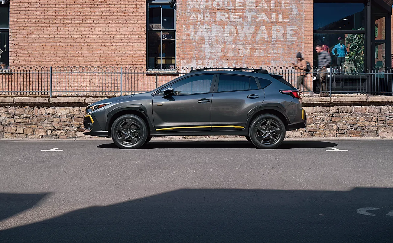 Grey 2026 Subaru Crosstrek Sport in profile alongside a brick wall