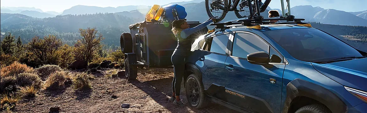Owner loading gear onto a blue 2026 Subaru Crosstrek at a high desert overlook