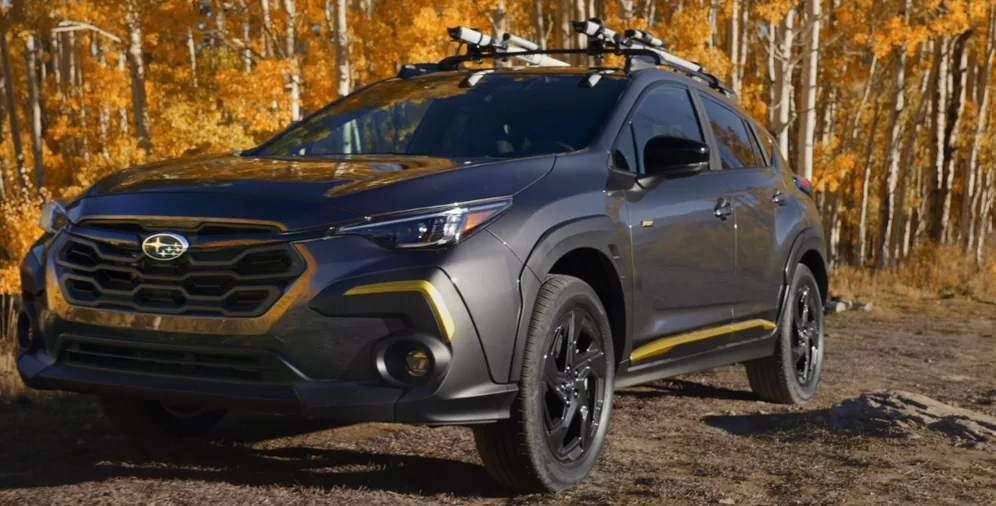 Grey 2026 Subaru Crosstrek Sport with yellow accents and skis on the roof in an aspen grove