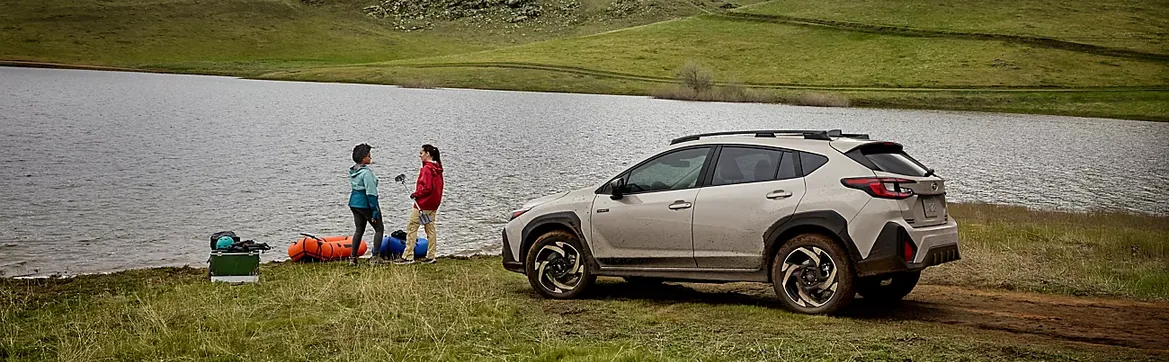 2026 Subaru Crosstrek Hybrid parked by a lake while two people unload gear