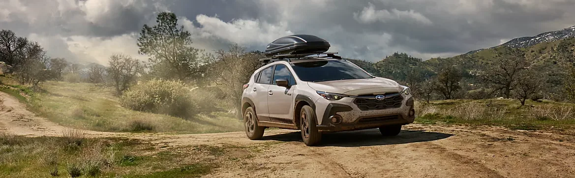 2026 Subaru Crosstrek Hybrid raising dust on a dirt trail under a stormy sky