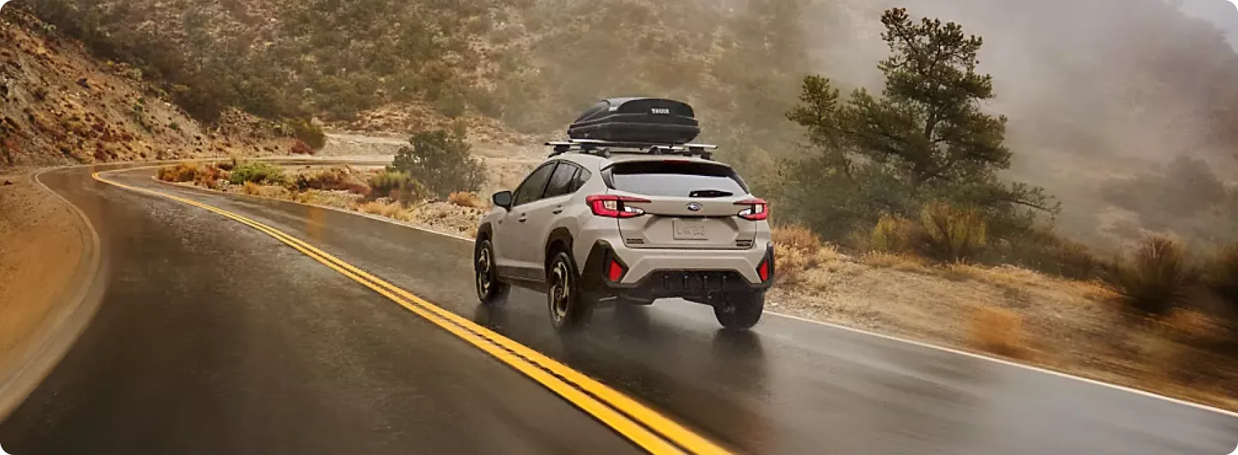 2026 Subaru Crosstrek Hybrid on a rain-slicked mountain highway