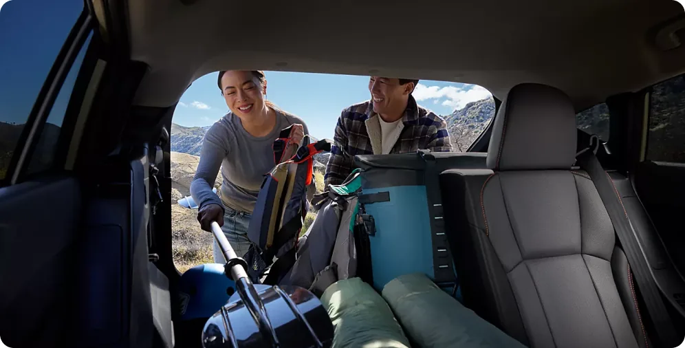 Two people loading luggage through the open rear gate of a 2026 Crosstrek Hybrid