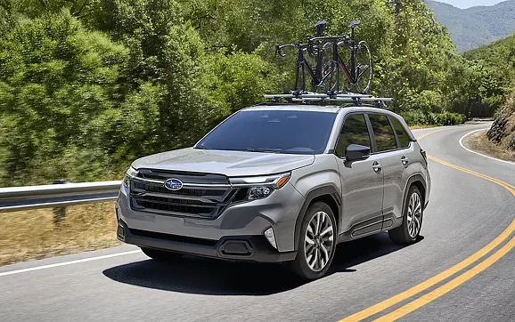 Silver 2026 Subaru Forester carrying bicycles on a mountain road