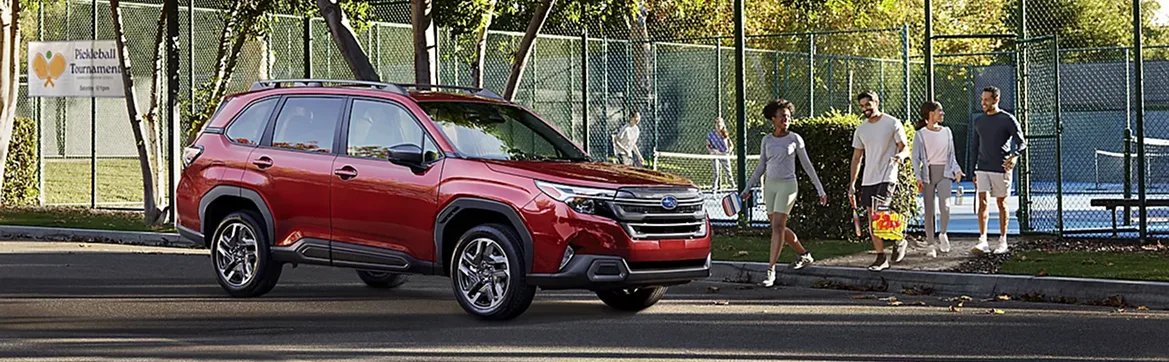 Red 2026 Subaru Forester parked beside a park tennis court