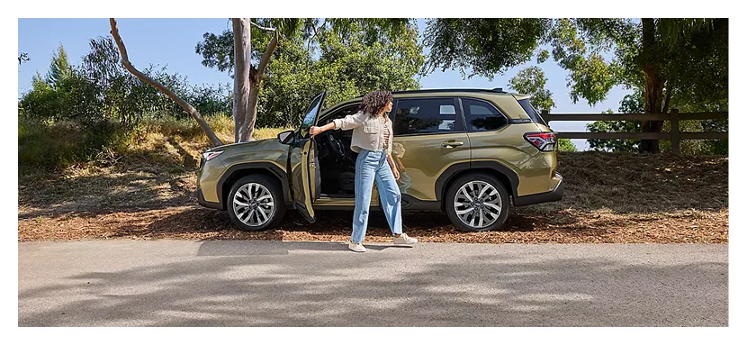 Owner standing beside a 2026 Subaru Forester Hybrid parked in a field