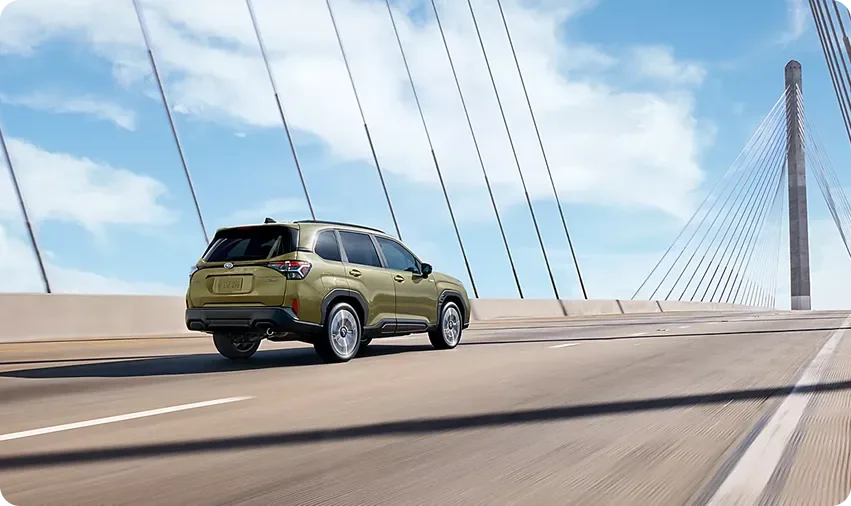 Olive green 2026 Subaru Forester Hybrid crossing a suspension bridge