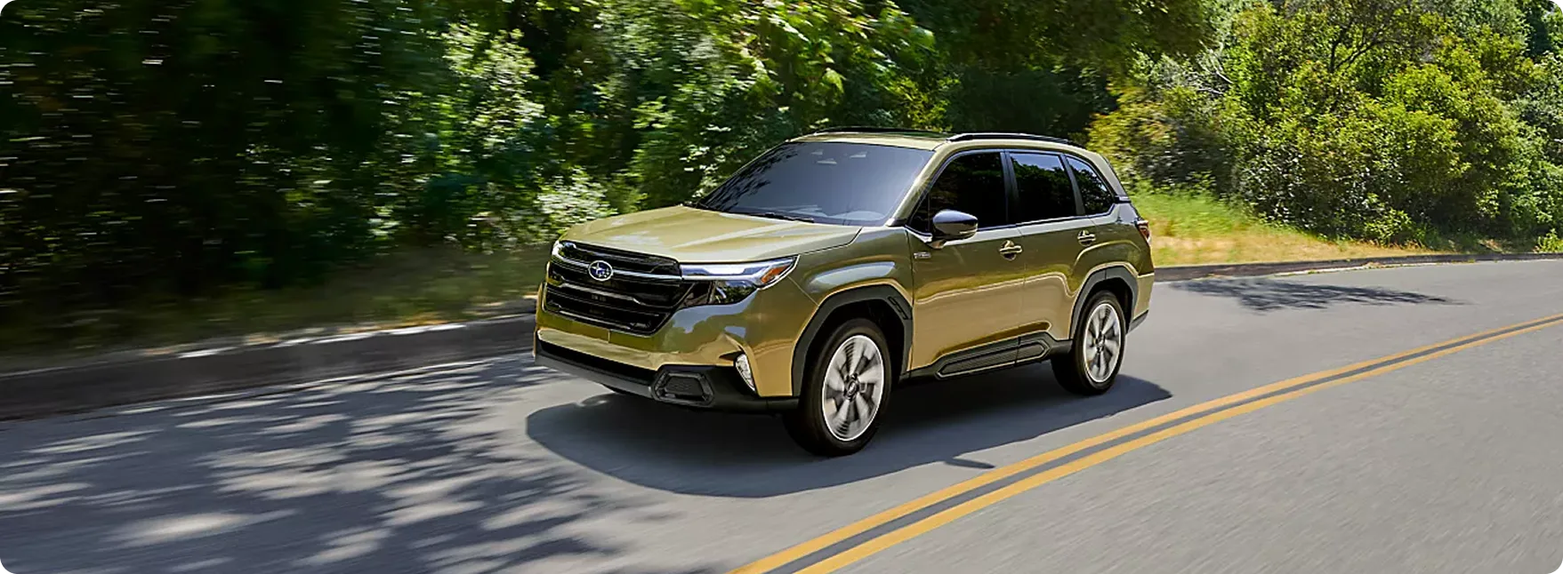 Olive green 2026 Subaru Forester Hybrid on a tree-lined road