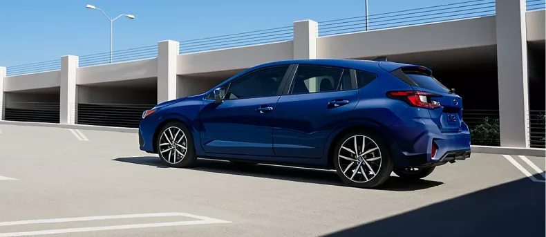 Blue 2026 Subaru Impreza pulling away under a highway overpass