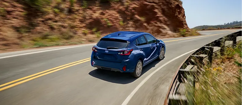 Blue 2026 Subaru Impreza on a winding cliffside road