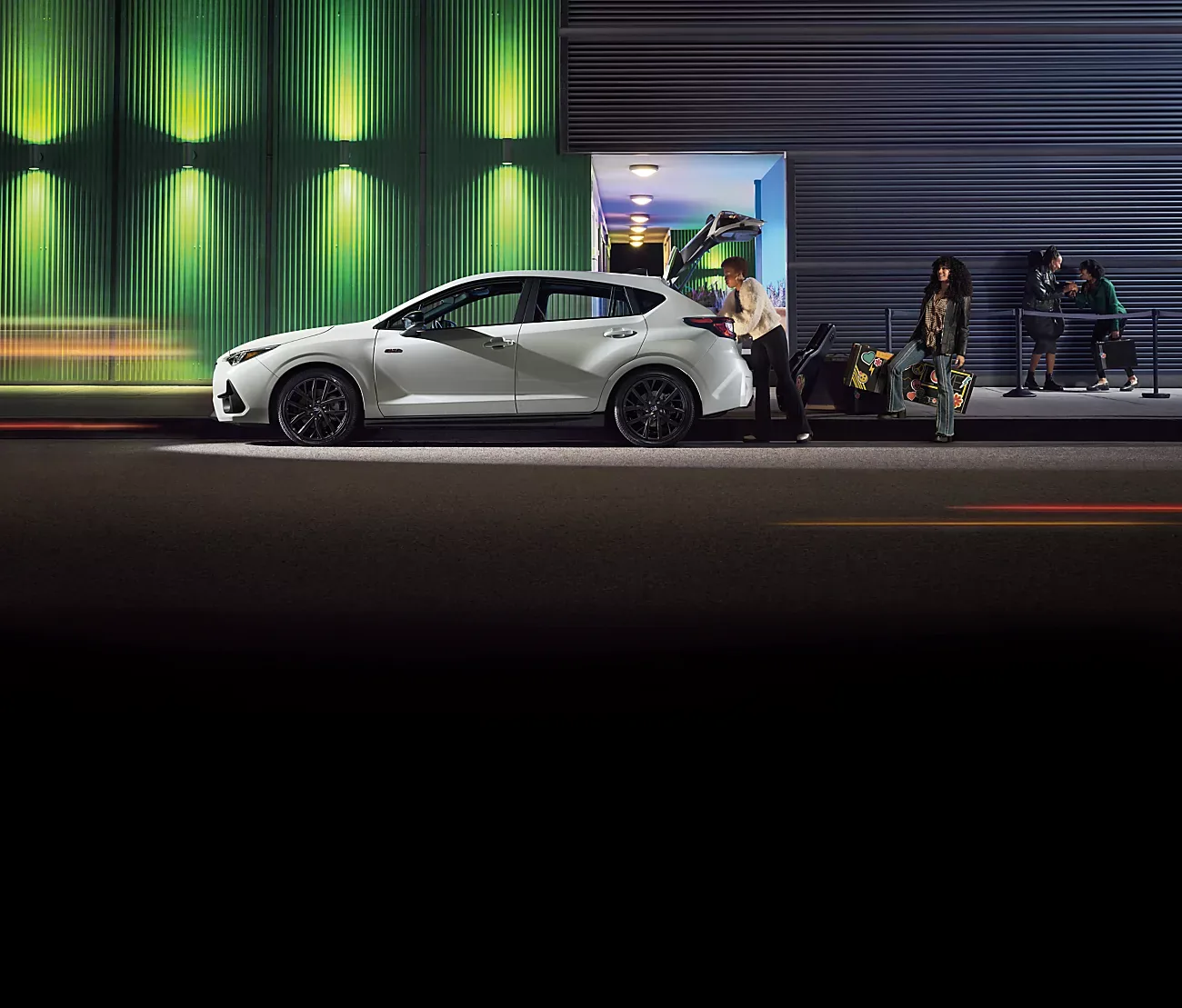 White 2026 Subaru Impreza loading up outside a venue at night