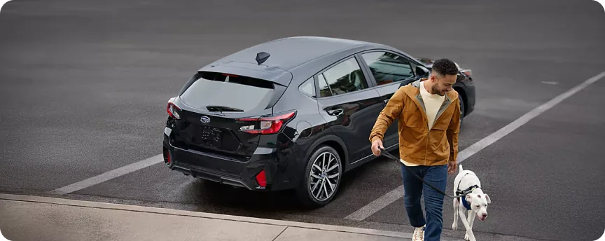 Owner walking a dog past the open hatch of a 2026 Subaru Impreza