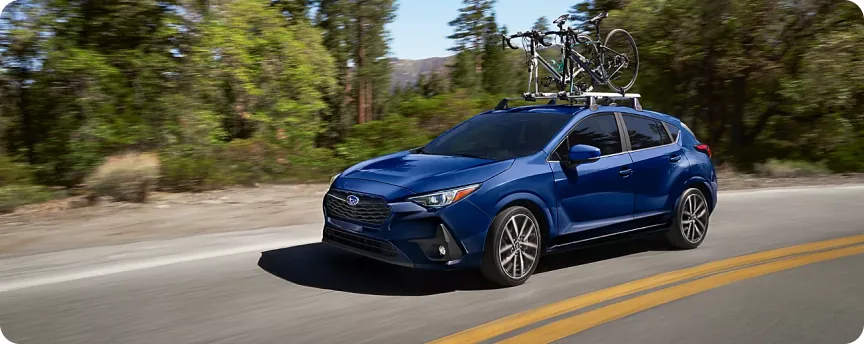 Blue 2026 Subaru Impreza carrying a bike on its roof crossbars