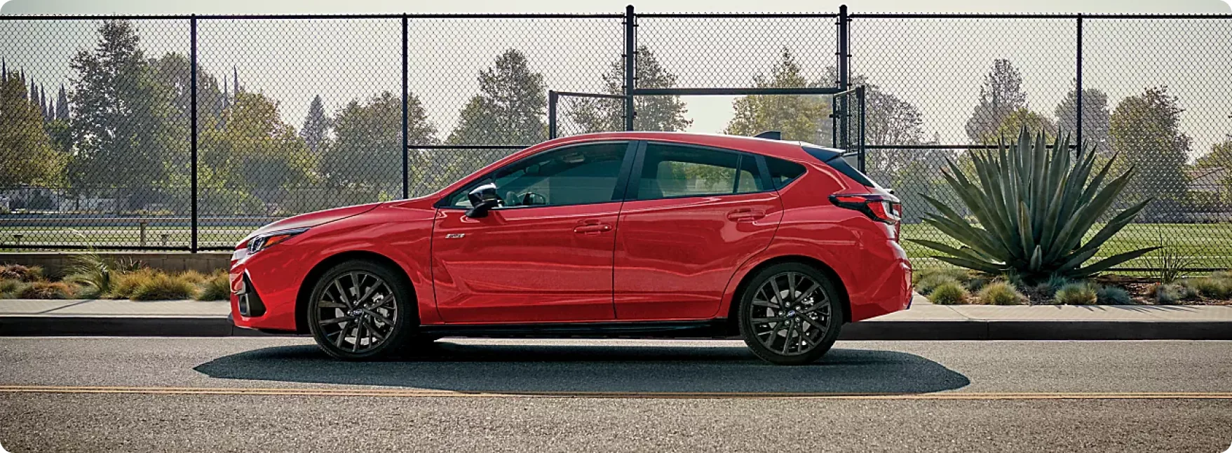 Red 2026 Subaru Impreza in profile alongside a sports court