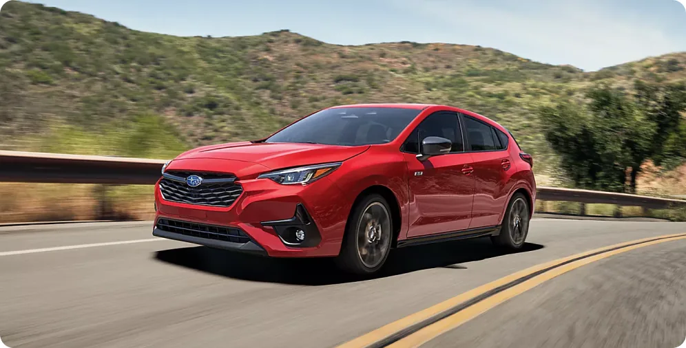 Red 2026 Subaru Impreza on a winding hillside road