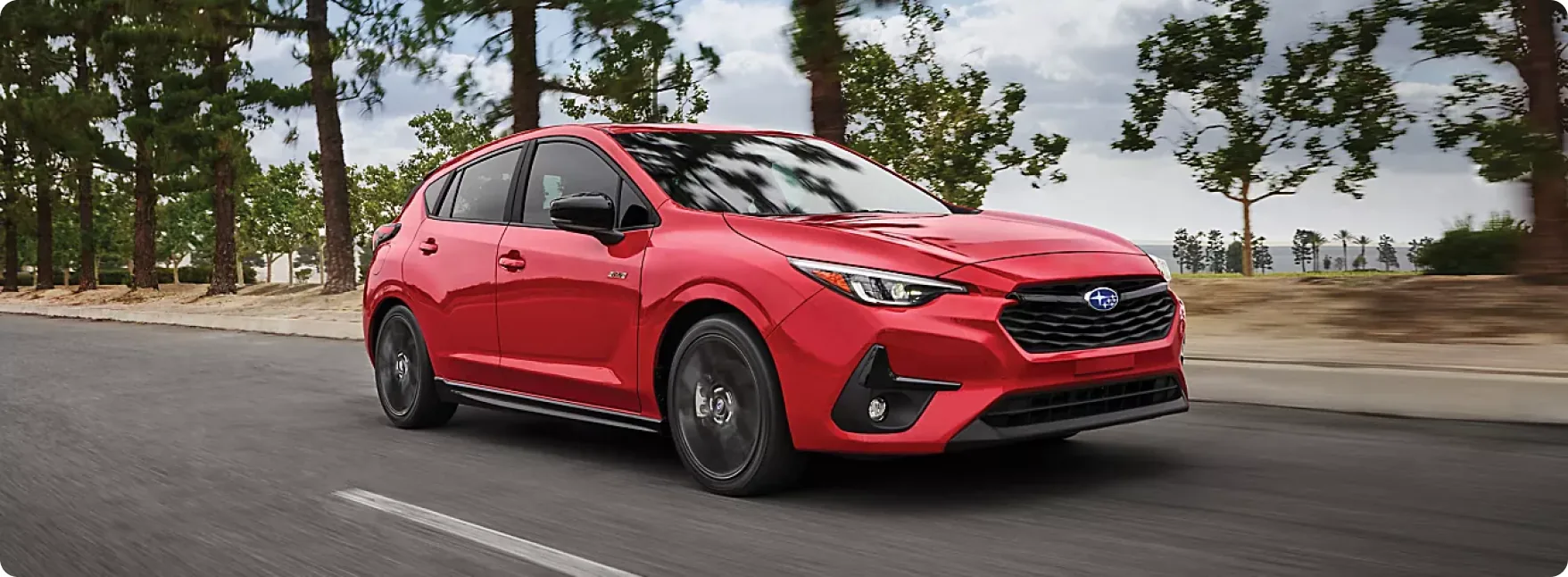 Red 2026 Subaru Impreza RS at speed on a tree-lined road