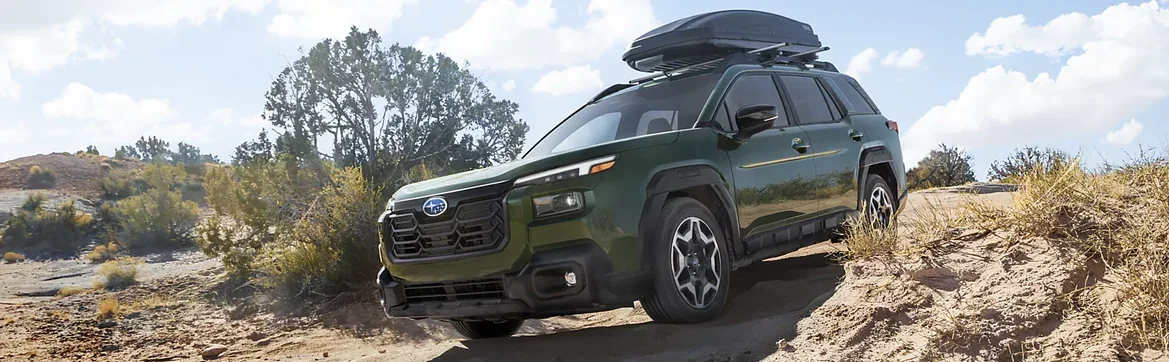 Green 2026 Subaru Outback with a roof cargo box in the desert