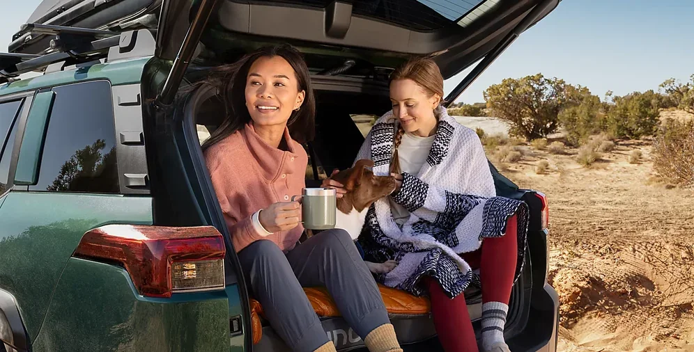 Two people relaxing in the open cargo area of a 2026 Subaru Outback