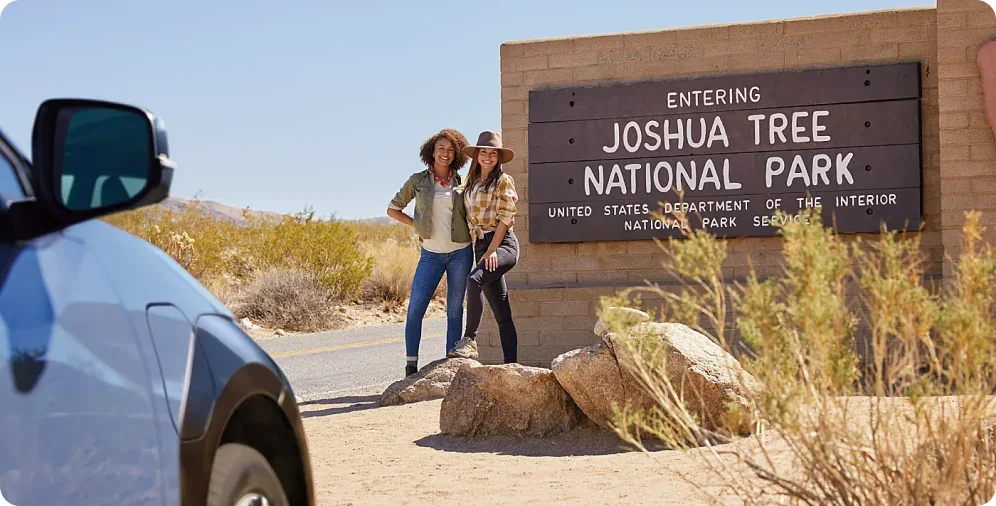 Travellers at the Joshua Tree National Park entrance sign beside a 2026 Subaru Solterra