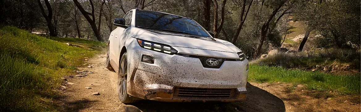 Mud-spattered 2026 Subaru Solterra on a wooded dirt trail