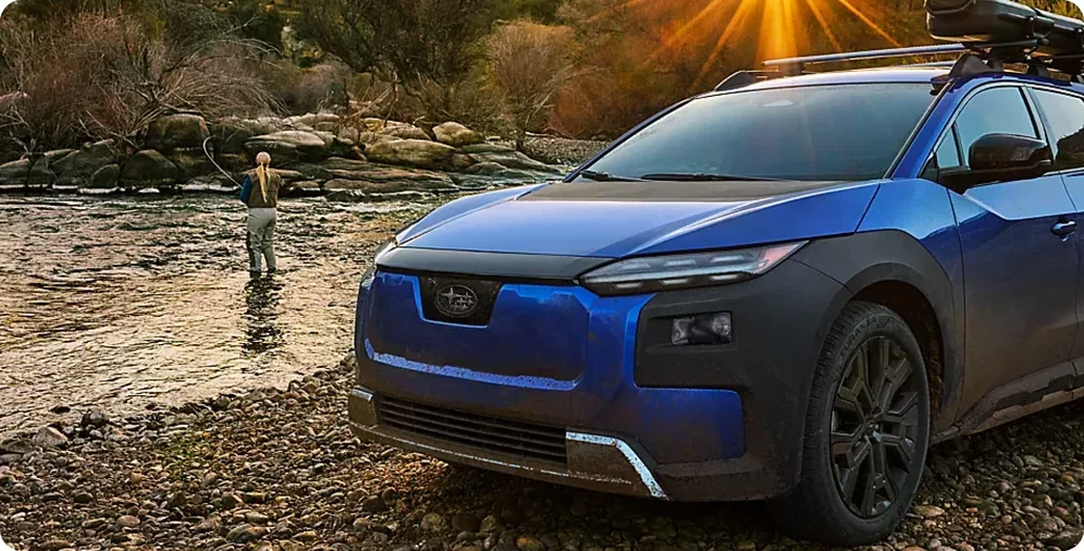 2026 Subaru Trailseeker parked by a river while an angler fishes at sunrise