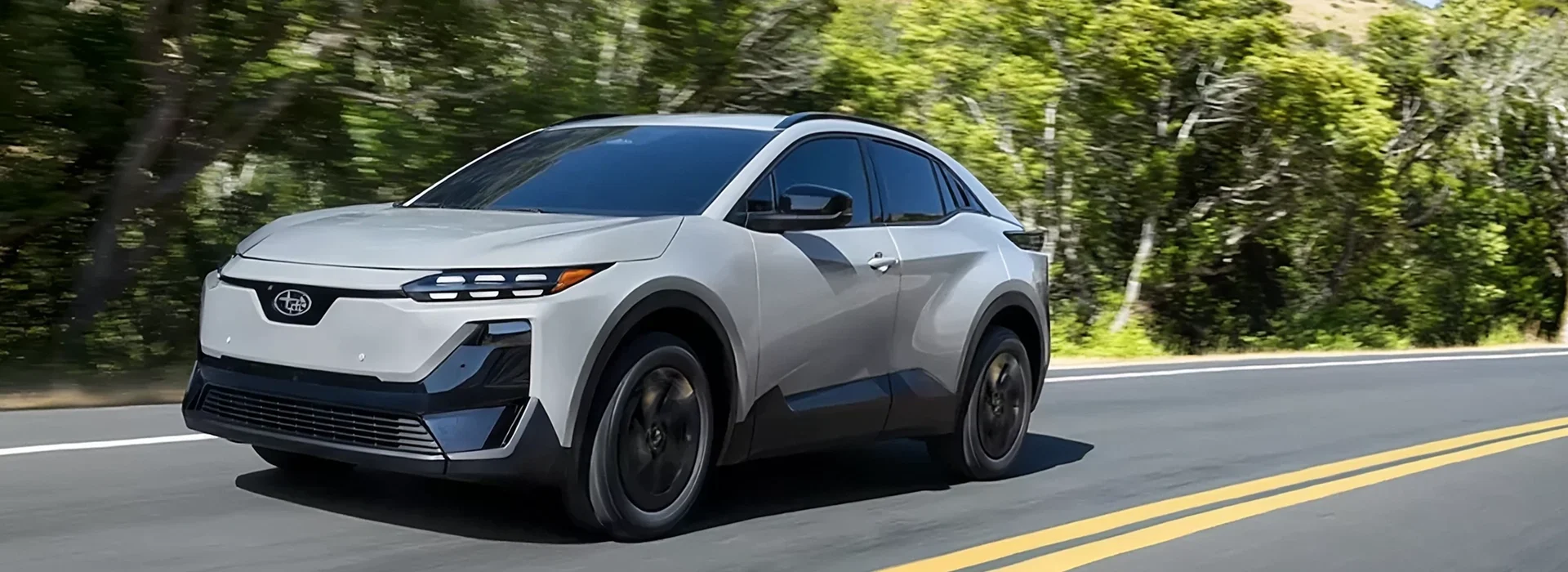 2026 Subaru Uncharted electric crossover driving a tree-lined road