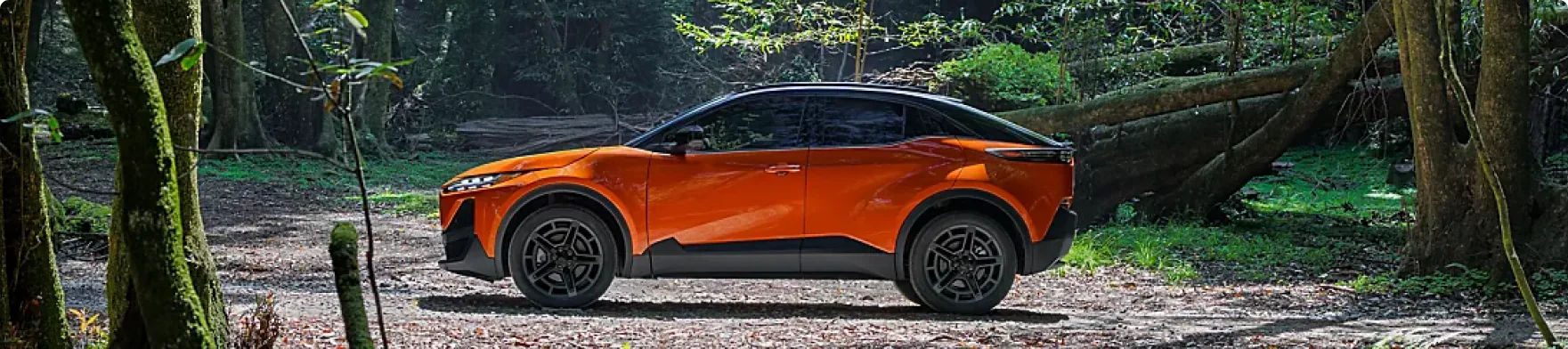 Side profile of an orange 2026 Subaru Uncharted parked on a forest trail