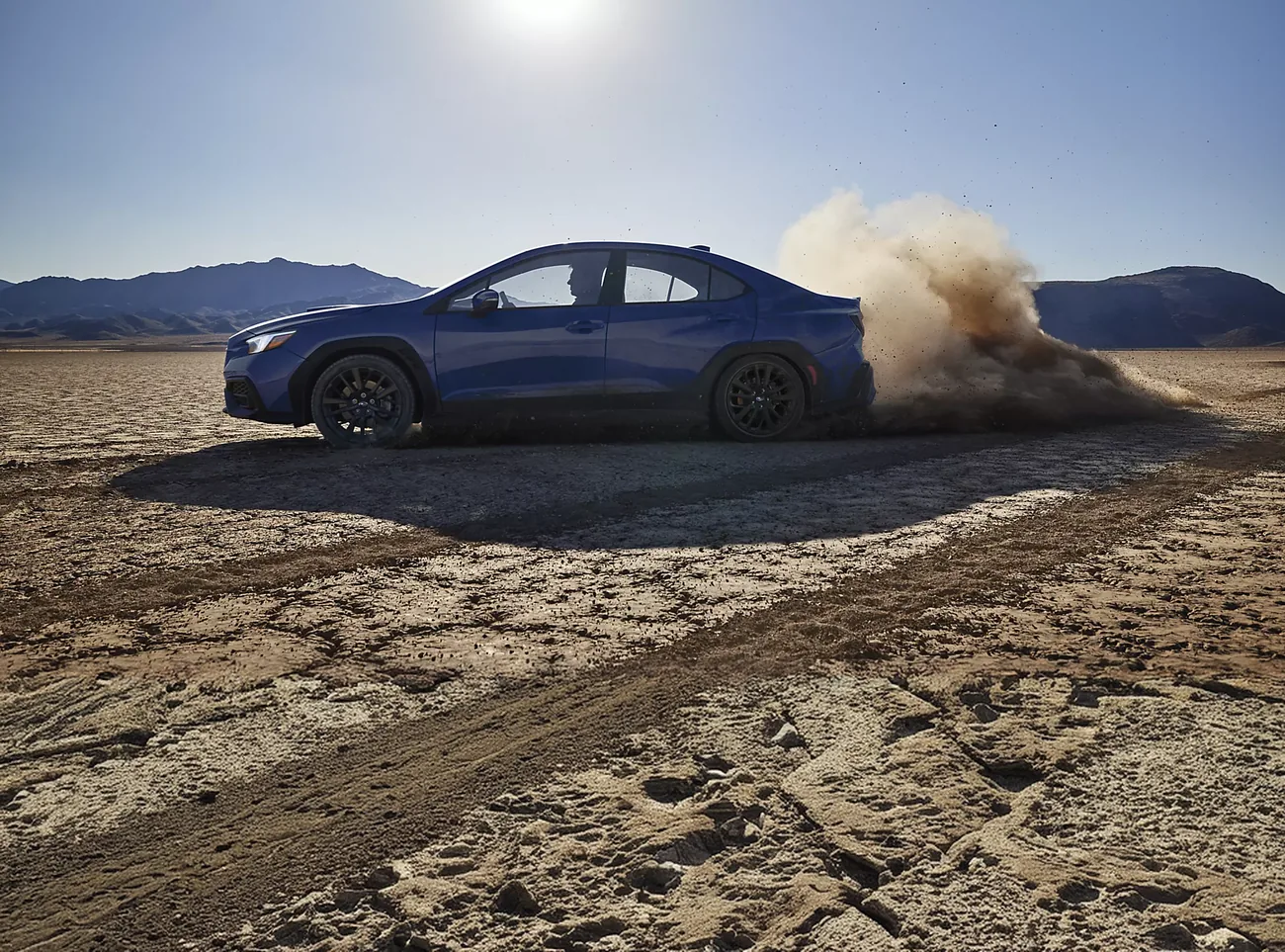 Blue 2026 Subaru WRX kicking up dust on a dry lake bed