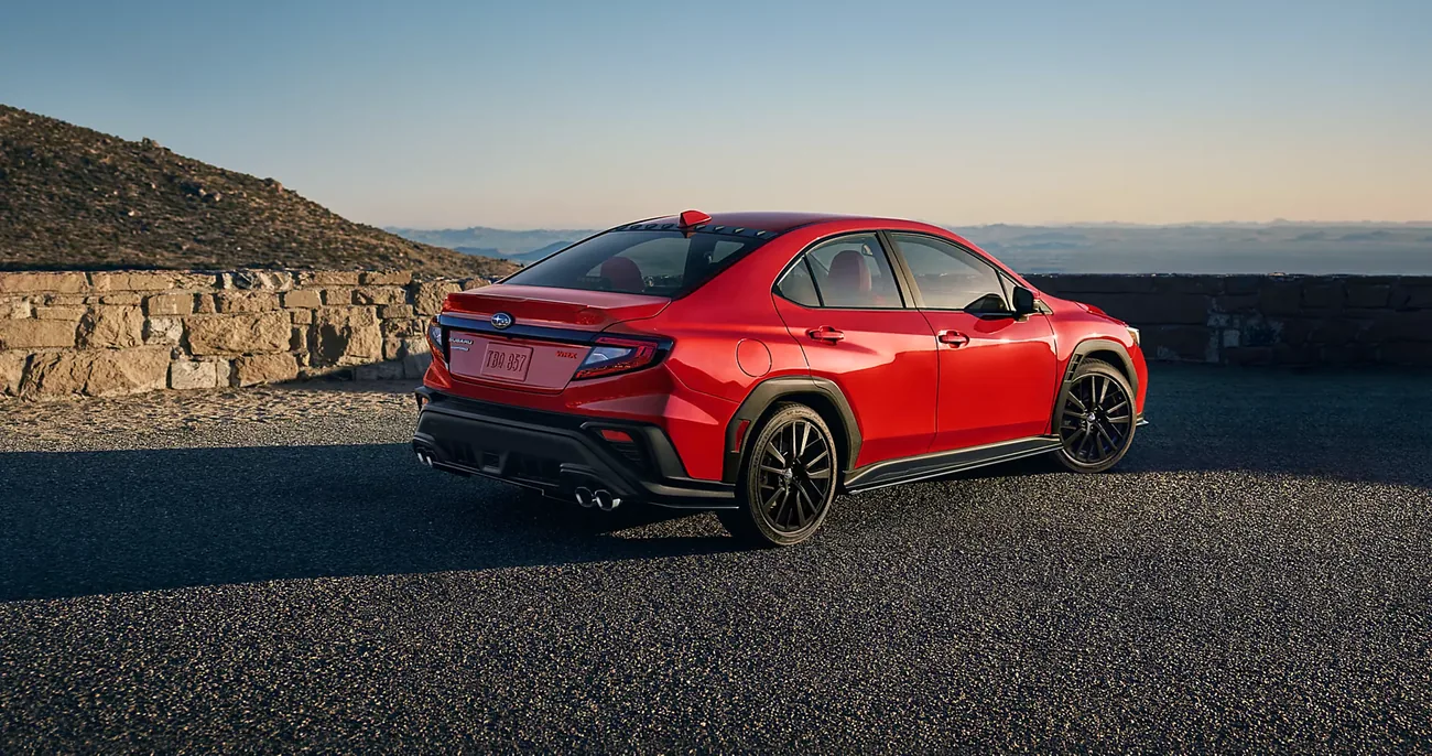 Rear three-quarter view of a red 2026 Subaru WRX at sunrise
