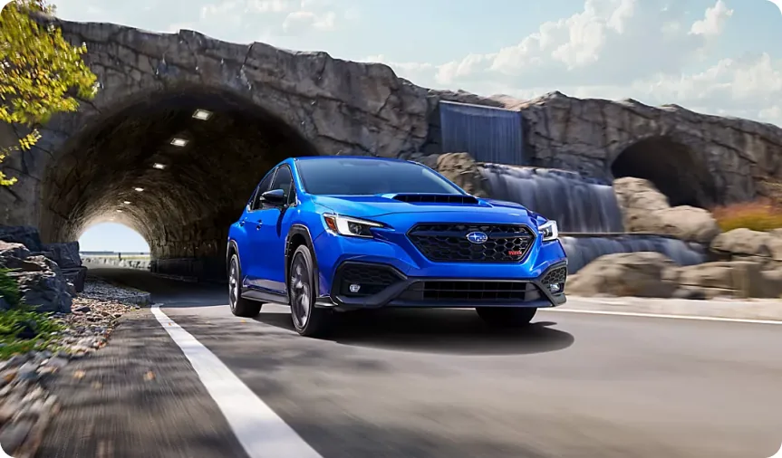Blue 2026 Subaru WRX tS emerging from a stone tunnel on a coastal road