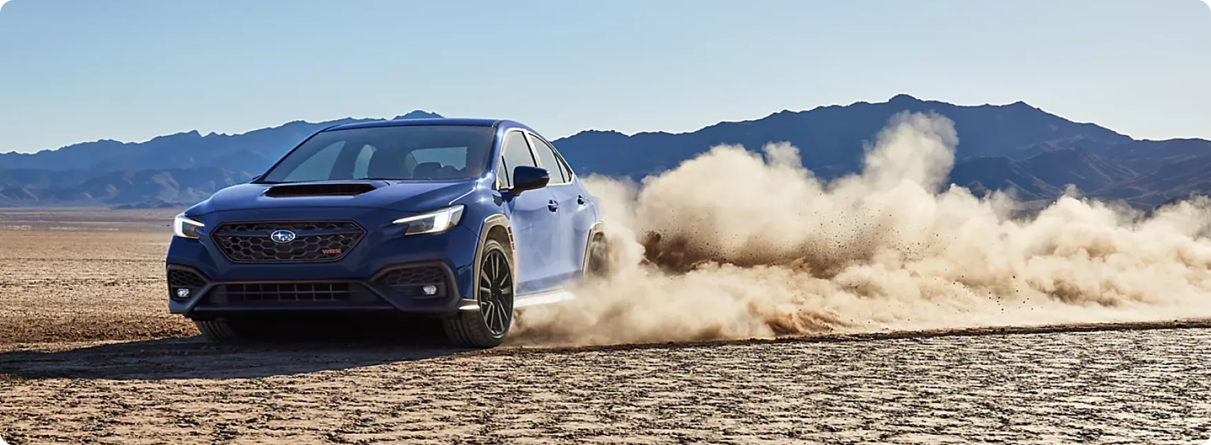 Blue 2026 Subaru WRX sliding across a dry lake bed in a cloud of dust