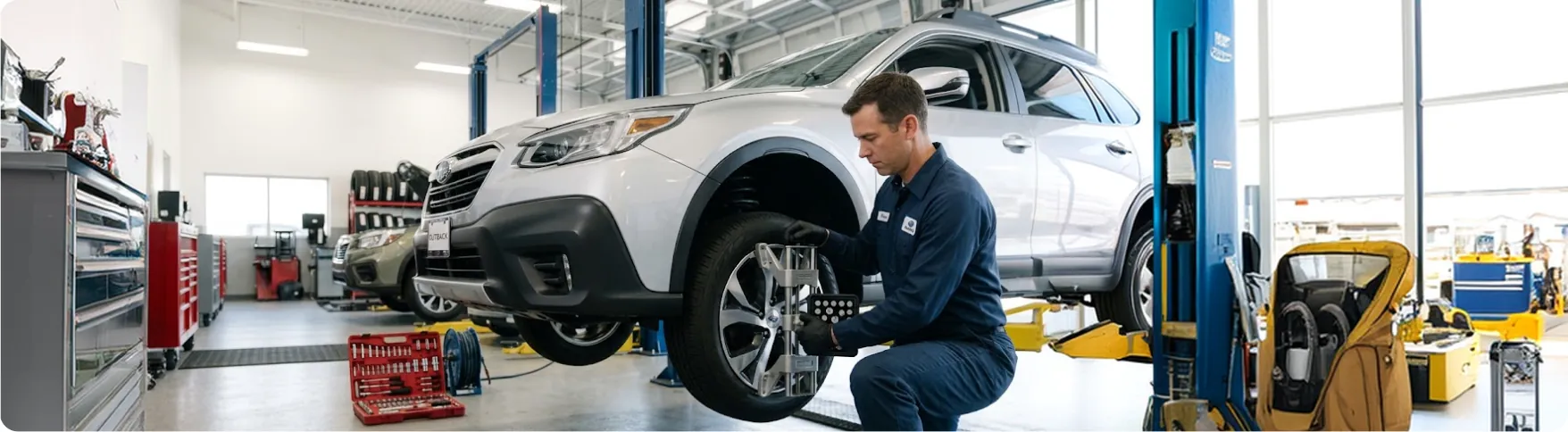 Briggs Subaru of Topeka technician fitting alignment sensors to a Subaru Outback wheel in Topeka, KS