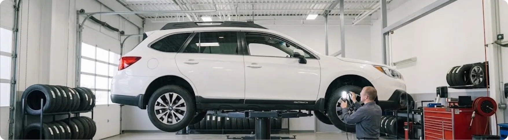 Briggs Subaru of Topeka technician checking suspension components under a raised Subaru Outback in Topeka, KS
