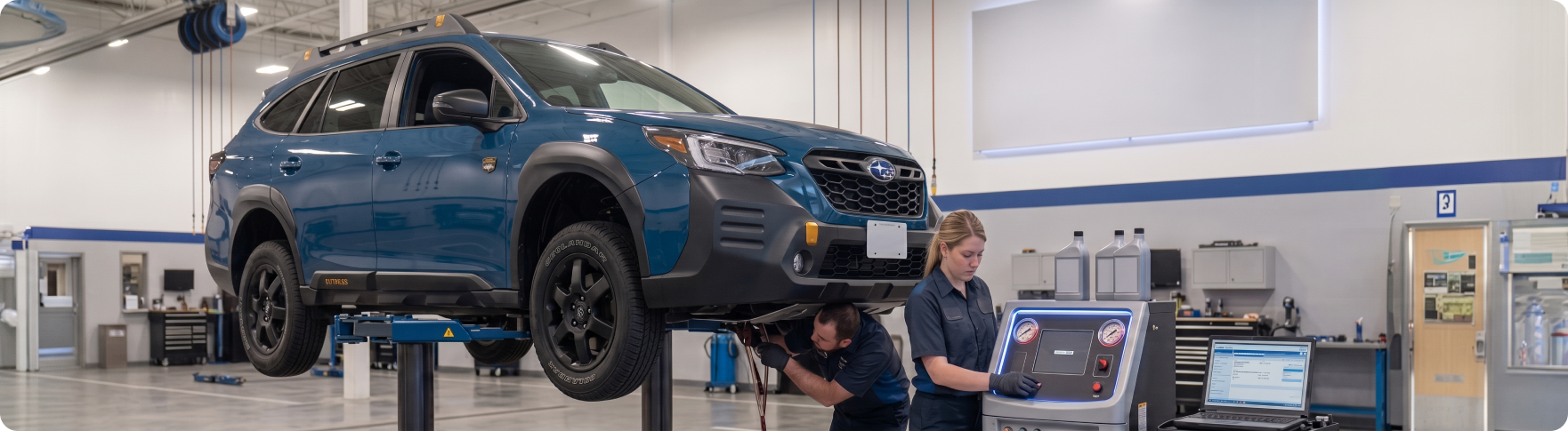 Subaru Outback raised on a service lift during a transmission fluid exchange at the Briggs Subaru of Topeka service department